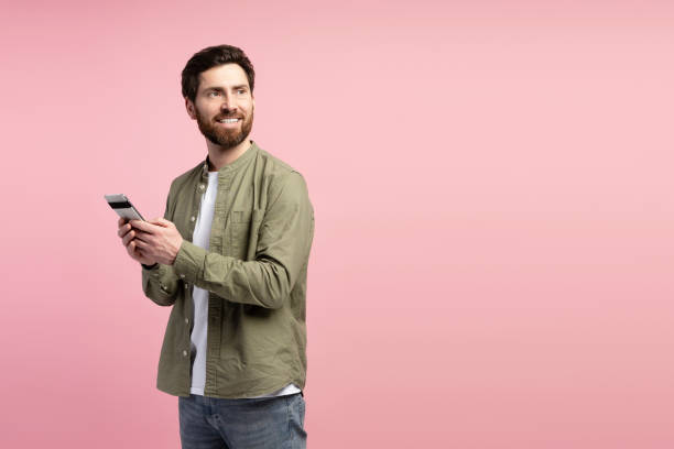 istock Happy Latin bearded man chatting on mobile phone, looking at copy space over pink background 2197740260