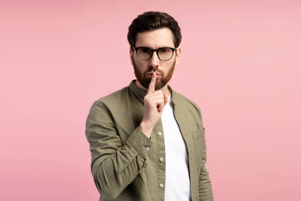 istock Bearded man in glasses holding finger on lips looking at camera, isolated on pink background 2197740285