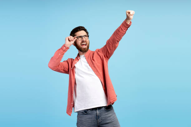 istock Bearded man in eyeglasses, screaming and holding hand up, isolated on blue background 2197740444