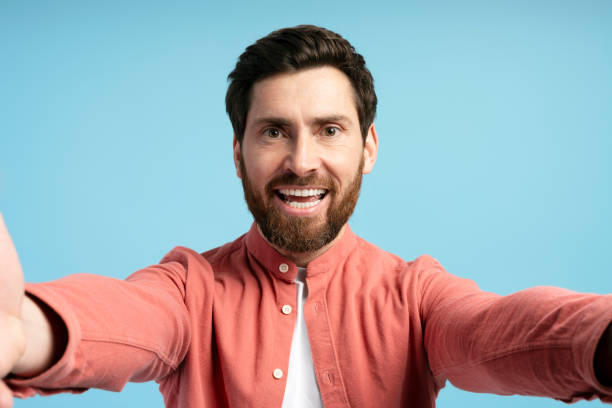 istock Smiling bearded man taking selfie on blue background 2197740456