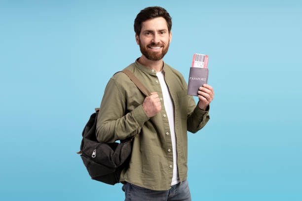 istock Smiling Latin young man holding passport and backpack, posing at camera in studio 2197740471