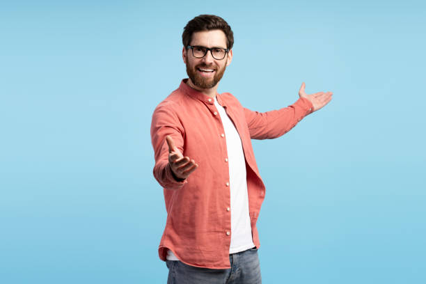 istock Smiling bearded man in glasses making a presentation by hands isolated on blue background 2197740476