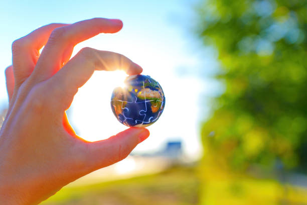istock Hand Holding Puzzle Globe Against Sunlit Background 2197741265