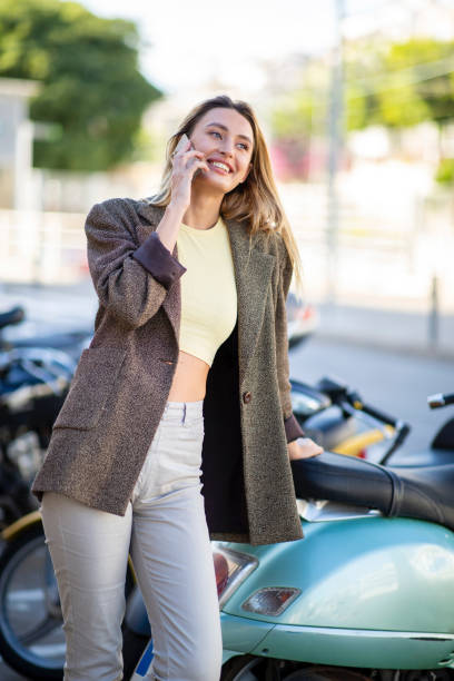 istock young woman talking with cellphone while leaning outdoors on scooter 2197743599
