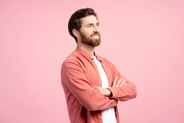 istock Smiling bearded man crossing arms standing isolated on pink background looking to copy space 2197743764