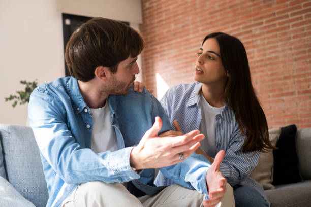 istock Couple struggling with their relationship sitting on the couch in silence at home, facing issues of infidelity, lack of trust, emotional disconnect, financial struggles, job loss, and discussing an uncertain future together 2197743901