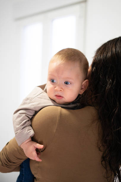 istock Mother holding her baby over her shoulder, looking away 2197744170