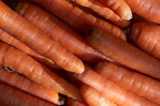 A close-up image of fresh, vibrant orange carrots stacked together, showcasing their natural textures and colors. Perfect for food-related projects and healthy eating themes.