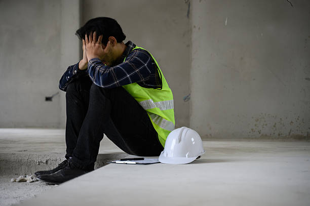 istock Young Asian male construction worker staff feeling sad and upset while sitting on the floor of the building construction site due to been fired from job cause by company bankruptcy economic recession. 2197749225