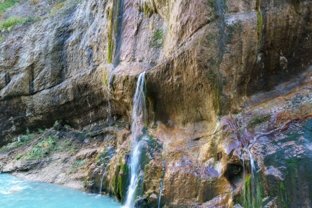 Scenic Chegem waterfalls, cascading down rugged, moss-covered cliff into tranquil pool below. Chegem River flow between steep cliffs with grottoes created by nature. Kabardino-Balkaria. Chegem Gorge