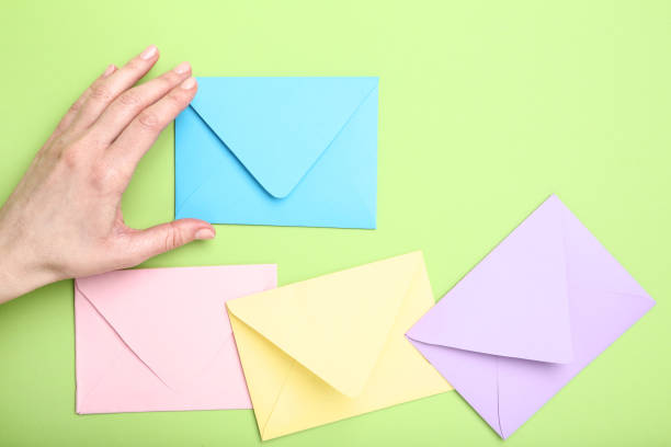 istock Female hand with colorful paper envelopes on green background 2197752824