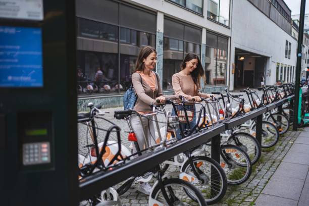 Two young women are renting bicycles at a bike sharing station in malmo, sweden, promoting sustainable urban transportation