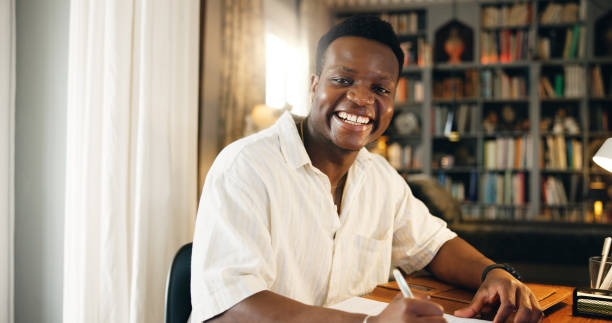 istock Black man, student and writing with portrait, home or happy for distance learning, development or progress. Person, notes and books with pride, education or scholarship for college project in Nigeria 2197758261
