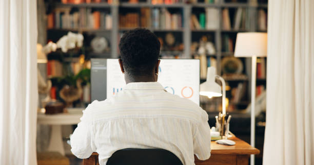 istock Computer, trading or back of man in home with graphs stats, review or progress report. Reading info, investor and charts on screen of pc monitor with markets for pattern, trends and peak in apartment 2197758302