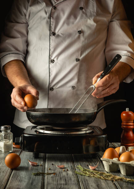 istock In a warm kitchen, a skilled chef holds a fresh egg and skillfully cracks it into a hot pan. The subtle steam rising adds an inviting atmosphere as ingredients await their transformation 2197759458
