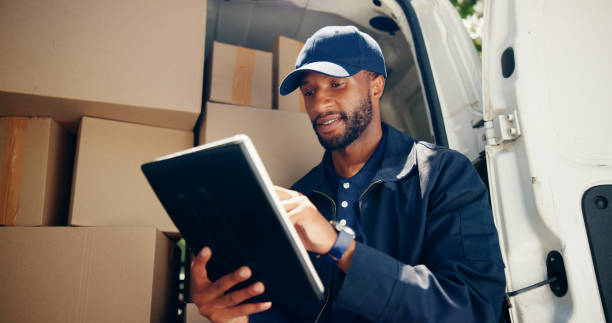 istock Courier, cargo or man with tablet by van for package distribution, online order checklist or supply chain. Logistics, transport or black driver with digital app for parcel location or inventory check 2197762759