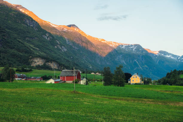 Majestic view of village on the fresh green meadow surrounded by sunset mountain peaks in Jostedalsbreen National park
