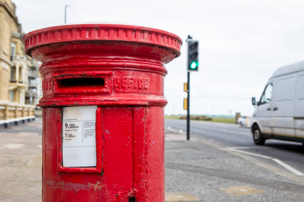 istock Red postbox and a van on a street by the sea 2197764044