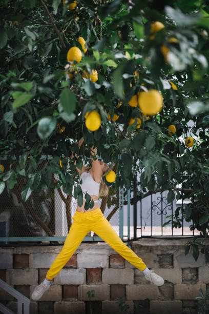 istock Young woman in yellow pants standing under lemon tree 2197765660