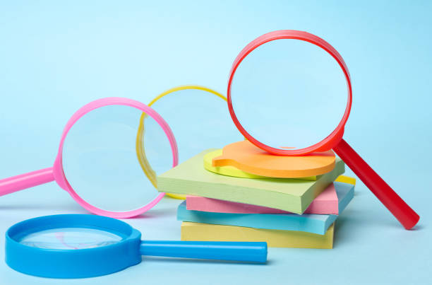 istock Multicolored plastic magnifying glasses on a blue background and paper notes 2197766578