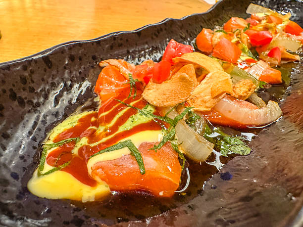 istock Elegant sushi assortment served on a black ceramic plate at a Japanese restaurant. A beautifully arranged selection of nigiri and maki rolls featuring fresh fish, rice, and garnishes, captured in a dimly lit dining ambiance. 2197768922