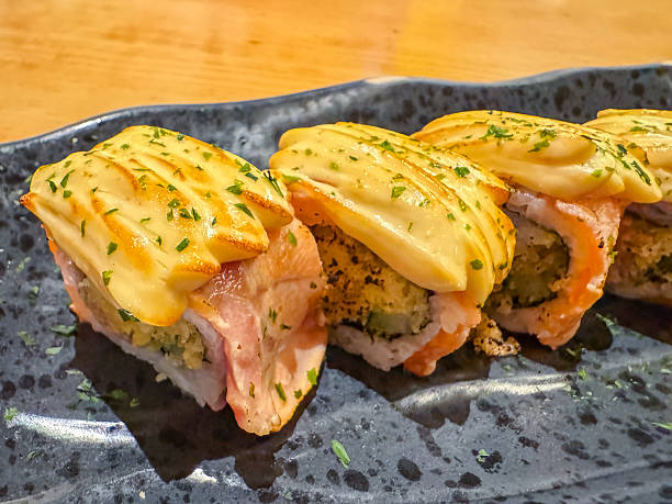 istock Elegant sushi assortment served on a black ceramic plate at a Japanese restaurant. A beautifully arranged selection of nigiri and maki rolls featuring fresh fish, rice, and garnishes, captured in a dimly lit dining ambiance. 2197769571