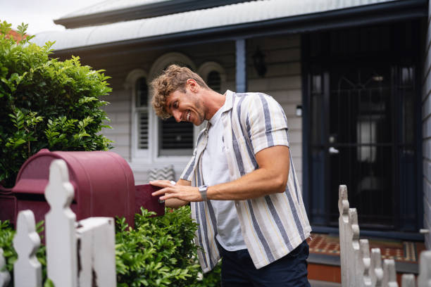 istock Young Man Checking Mail Outside a Cozy Suburban Home 2197780581