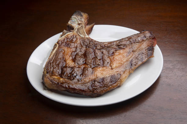 Grilled t-bone steak on white plate, offering a delicious culinary experience