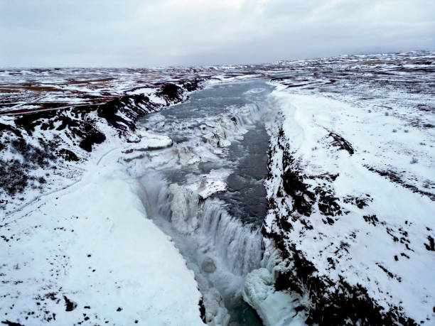 Majestic Gullfoss waterfalls form a half frozen triangle as the Hvita River falls into a wintry gorge in Western Iceland