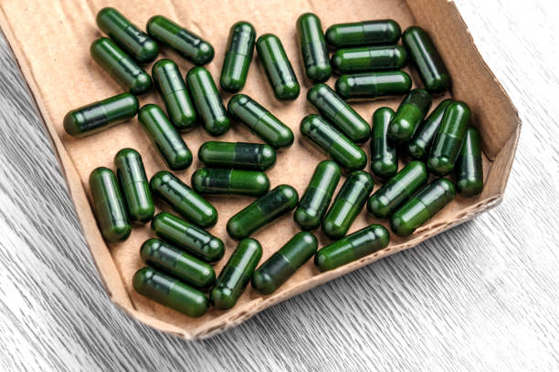 Green spirulina pills with multivitamins on a white background. Free space