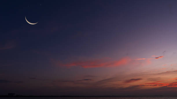 istock Crescent moon on twilight sky in evening vertical with colorful sunlight after sundown, symbol Islamic religion Ramadan, Dusk sky space backgrounds well for Arabic text present Eid al Adha, Eid ul fitr. 2197789340