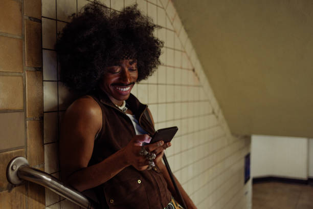 istock Stylish musician smiling and using phone in subway station 2197789532
