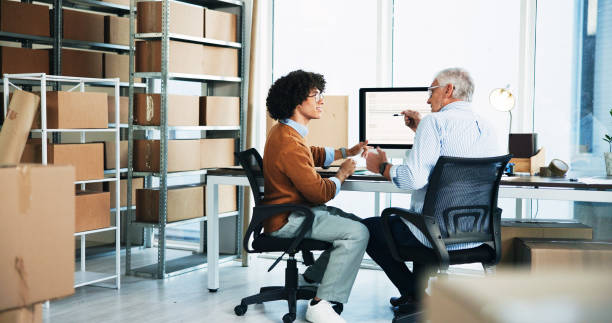 istock People, discussion and computer for distribution in office of schedule planning, order info and logistics. Back, men and talking of ecommerce delivery, product packaging and supply chain at warehouse 2197790583