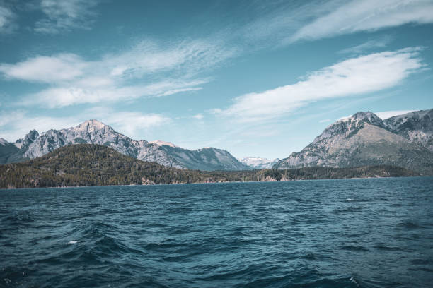 Stunning view of majestic mountains, lush forests, and a serene lake under a vivid blue sky, evoking peace and wonder at the beauty of nature.