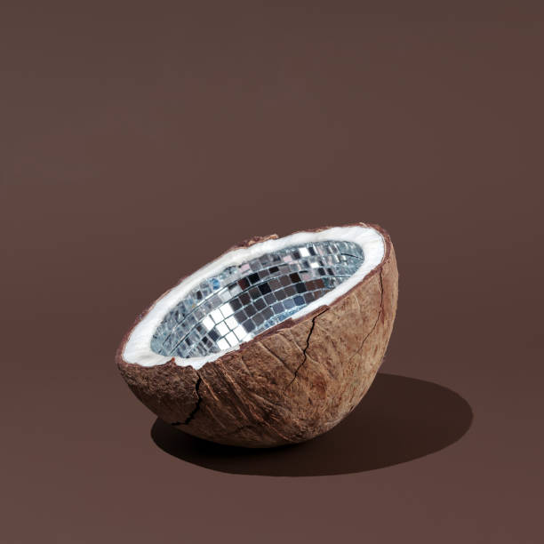 istock Halved coconut shell with mirror mosaic interior on smooth brown background in minimal studio setup. Creative holiday concept 2197793619