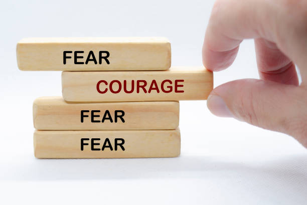 istock Hand pulling out wooden block with text saying COURAGE to separate from other wooden blocks with text FEAR. Courage and Speak Up concept 2197799819