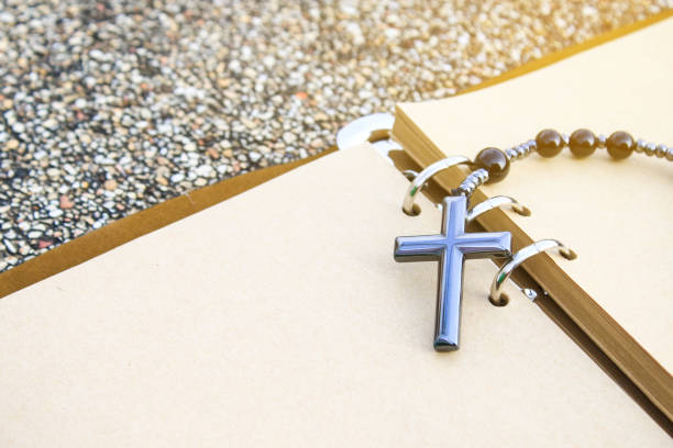 A shiny metal cross rests on an open brown notebook, symbolizing faith, reflection, and devotion. This image represents spiritual journaling, personal prayers, and religious contemplation.