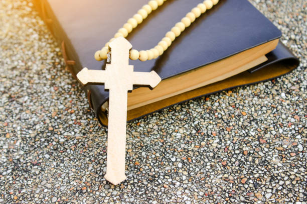A white ivory cross placed on a dark brown notebook reflects purity, peace, and divine guidance. The contrast symbolizes light amidst darkness, faith, and personal devotion.