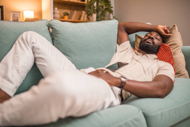 istock A black man is sleeping in the living room, while his mobile phone is on his stomach 2197804355