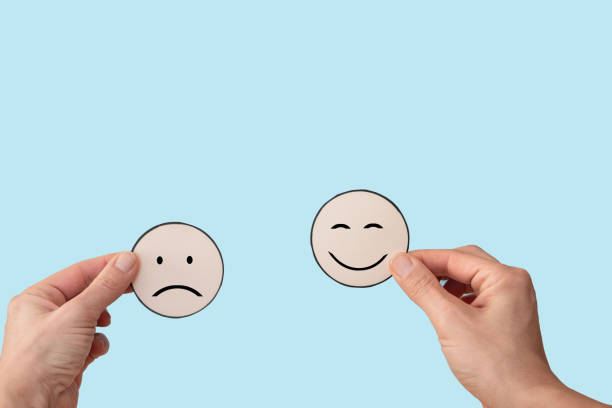 istock Hands holding two faces with smile and sad mood on blue background, customer rating or mental health concept 2197804966