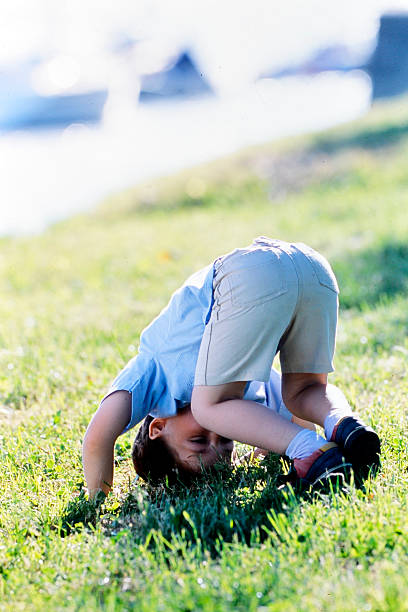 little boy doing somersaults on the grass in the garden