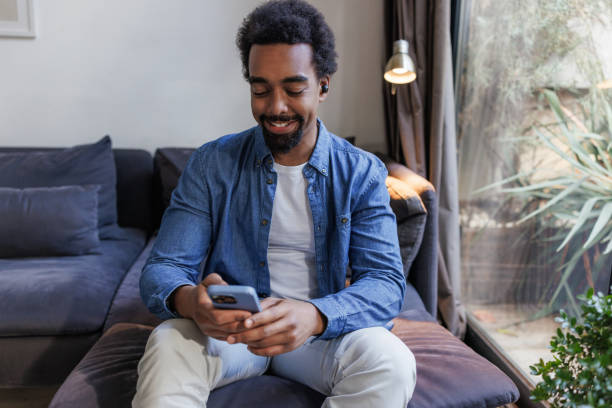 istock African-American man using smart phone on the sofa 2197810077