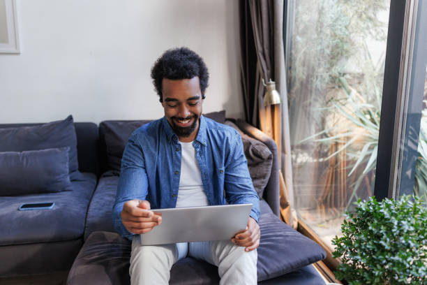 istock Smiling young man working on a laptop at home 2197810095