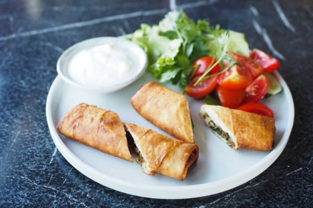 istock Enjoy delectable crispy rolls served alongside a vibrant fresh salad and a tangy yogurt dip 2197817997
