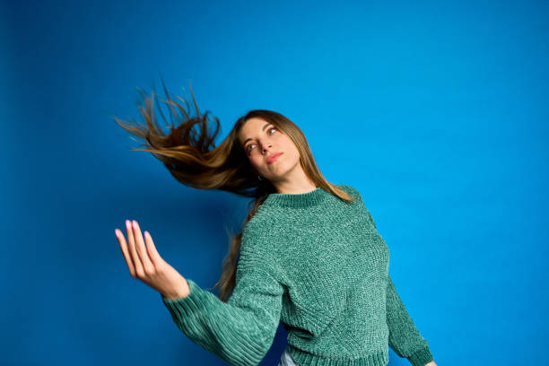 istock Young woman with long hair flowing in studio with blue backdrop 2197818053