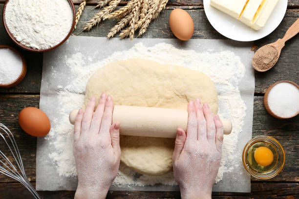 istock Female hands rolling dough on wooden table 2197823034
