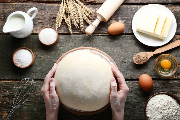 istock Female hands holding raw dough with eggs and butter on wooden table 2197823155
