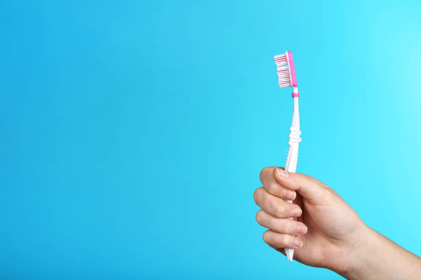 istock Female hand holding toothbrush on blue background 2197823734