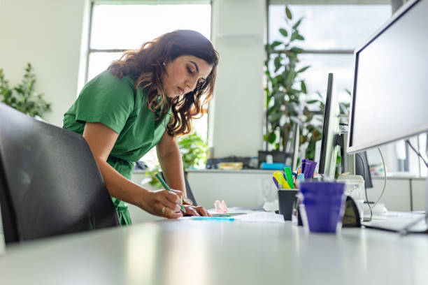 istock Working professional in green outfit focuses on tasks while surrounded by plants in modern Sydney office environment 2197825769
