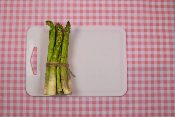 Green asparagus on a whiteboard, arranged on a pink checkered tablecloth